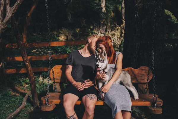 Hermosa pareja junto con perro en un columpio — Foto de Stock