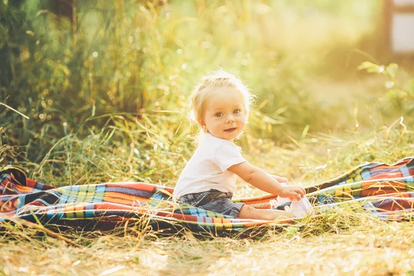 Little girl sitting on the lawn — Stock Photo, Image