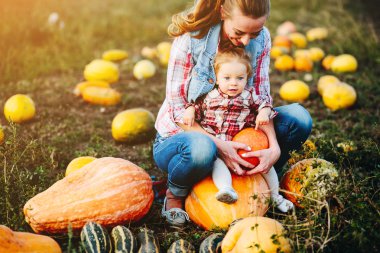 Anne ve kızı kabaklar üzerinde oturan