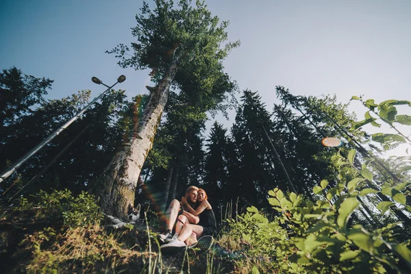 Belo casal sentado em uma floresta perto da árvore — Fotografia de Stock