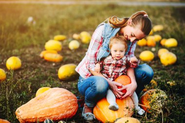 Anne ve kızı kabaklar üzerinde oturan