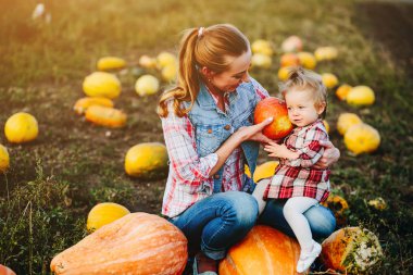 Anne ve kızı kabaklar üzerinde oturan