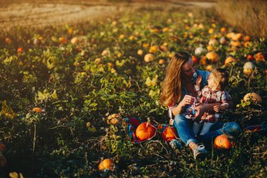 Anne ve kızı balkabaklarıyla bir tarlada.