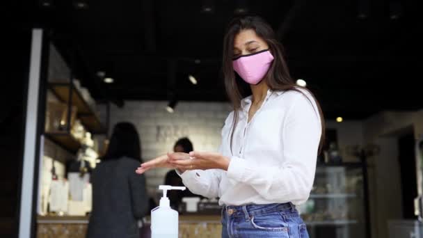 ผู้หญิงที่ใช้เจลล้างพิษ ทําความสะอาดมือของไวรัสโคโรนาที่คาเฟ่ . — วีดีโอสต็อก