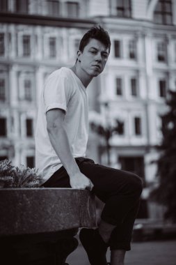 Şehir caddesinde oturan adam, kameraya bak ve etrafına bak.