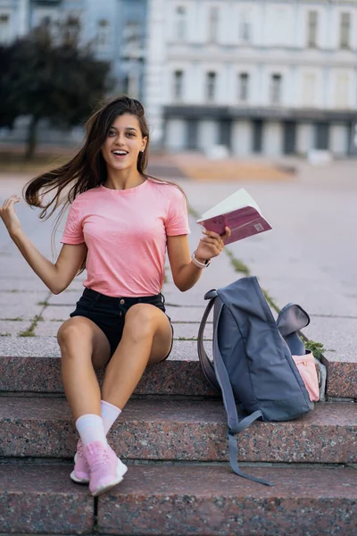 Glada ung kvinna tar anteckningar när du sitter på trappor utomhus — Stockfoto