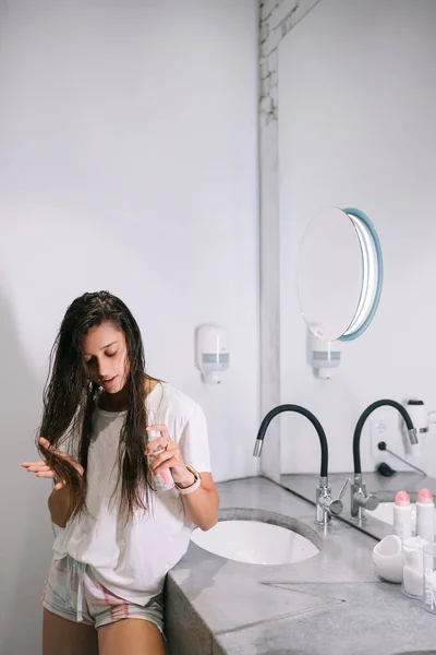 Jonge vrouw houdt hand in hand tot punt toont aan camera, zorg product fles — Stockfoto