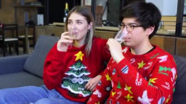 Bilgisayarlı mutlu çift kanepede birlikte, gülümseyen genç kız ve erkek evde eğleniyor.