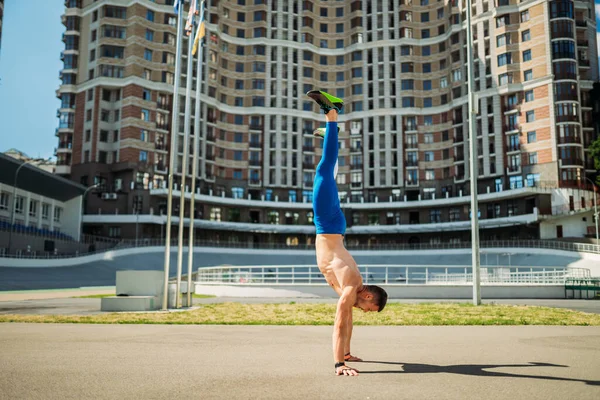 Musclé mec se tient sur ses mains contre un d'un grand bâtiment — Photo