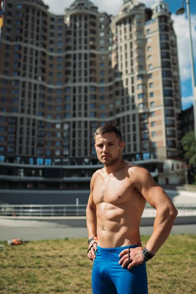 Мускулистый парень с обнаженным туловищем на фоне высокого здания — стоковое фото