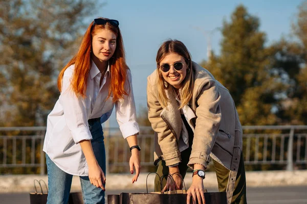 Unga kvinnor med shoppingväskor på parkering — Stockfoto