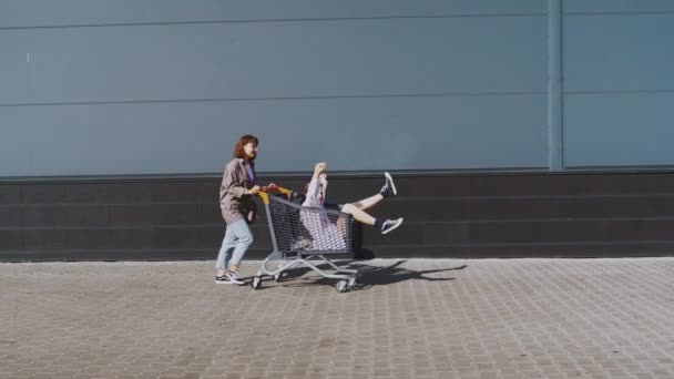 Flickvänner rida i en vagn på snabbköpet på gatorna i staden. — Stockvideo