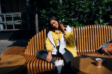 Esmer kız eski şehrin merkezinde bankta oturuyor..