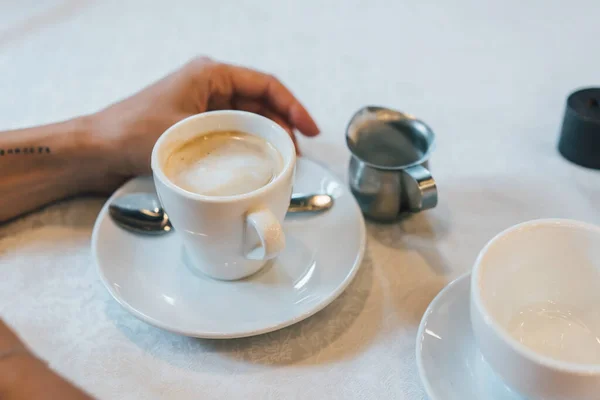 Mała biała filiżanka cappuccino stoi na stole — Zdjęcie stockowe