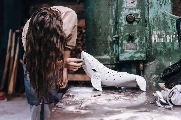Portrait of young woman carefully work on a ceramic whale in workshop. — Stok Foto