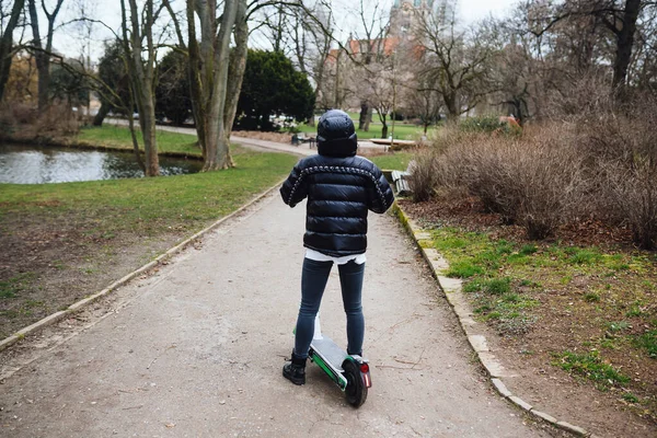 Modern meisje paardrijden een ecologische elektrische scooter in het park. — Stockfoto