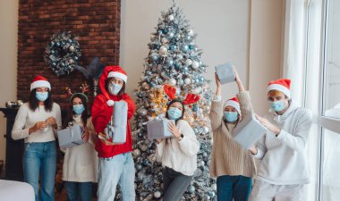 Noel Baba şapkalı, elinde hediyeler olan çok ırklı bir arkadaş grubu..