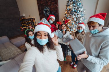 Noel Baba şapkalı, elinde hediyeler olan çok ırklı bir arkadaş grubu..