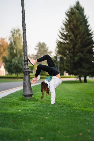 Attraktive dünne Frau macht eine Rückbiegung, während sie einen Salto zeigt. — Stockfoto