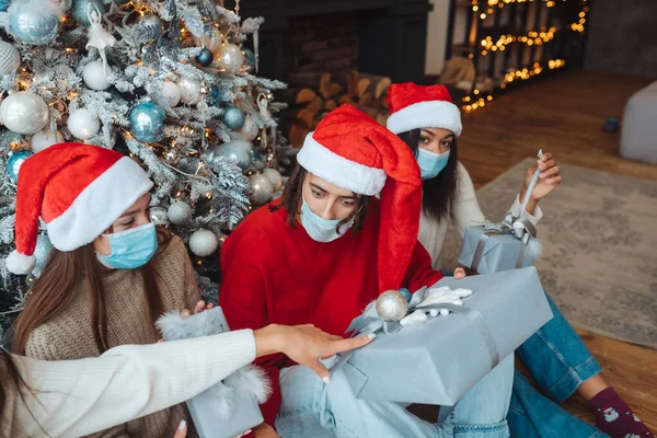 Багатоетнічна група друзів у Санта-капелюхах з подарунками в руках . — стокове фото
