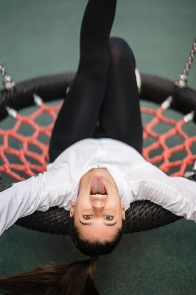 Jeune femme monte sur une balançoire à l'aire de jeux. — Photo