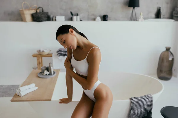 Привлекательная женщина в нижнем белье позирует рядом с ванной — стоковое фото