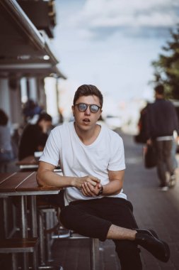 Şehir caddesinde oturan adam, kameraya bak ve etrafına bak.