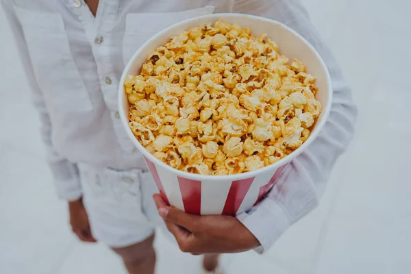 Close-up foto van een jong lief meisje, die een tube popcorn in haar handen houdt. — Stockfoto