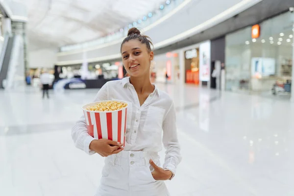Junge süße Frau hält Popcorn im Hintergrund des Einkaufszentrums — Stockfoto