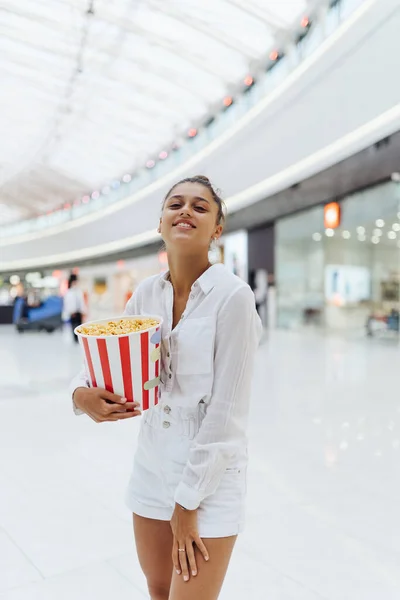 Jong schattig vrouw houden popcorn in het winkelcentrum achtergrond — Stockfoto