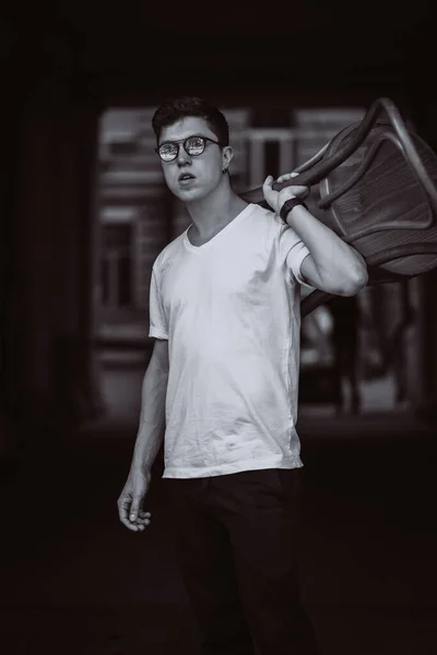 Портрет чоловіків, що стоять зі стільцем у білій футболці та сонцезахисних окулярах на вулиці — стокове фото
