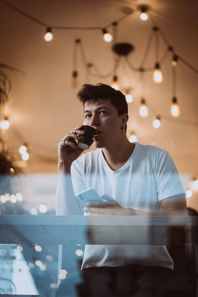 Ung, stilig man dricker sitt morgonkaffe på ett café.. — Stockfoto