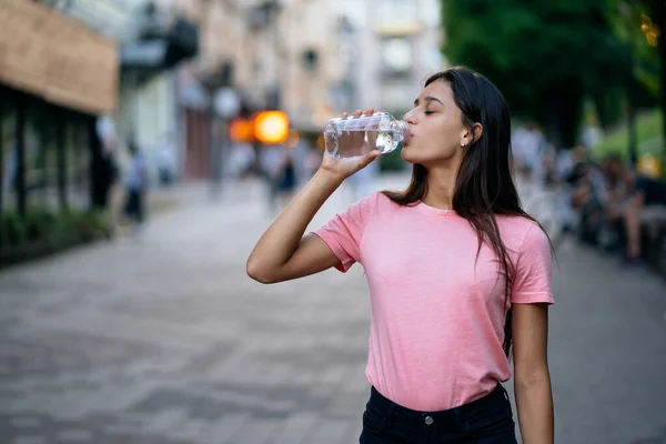 Bela menina bebe com uma garrafa de água — Fotografia de Stock