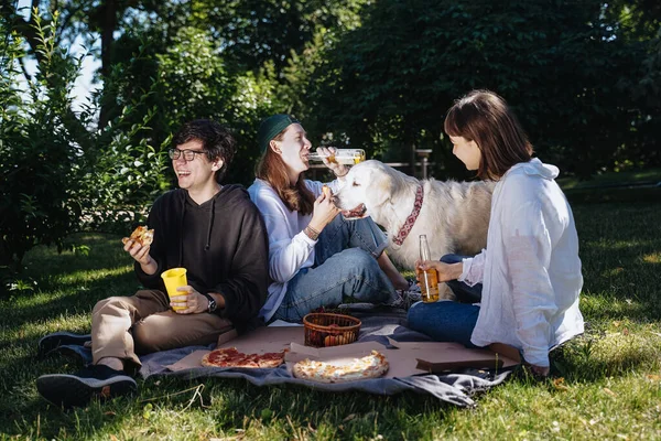 Társasága gyönyörű fiatalok és a kutya, hogy egy szabadtéri ebéd. — Stock Fotó