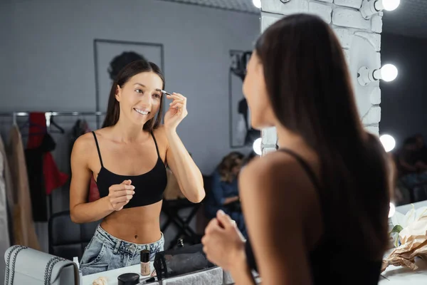 Reflection of young beautiful woman applying her make-up — Stock Photo, Image