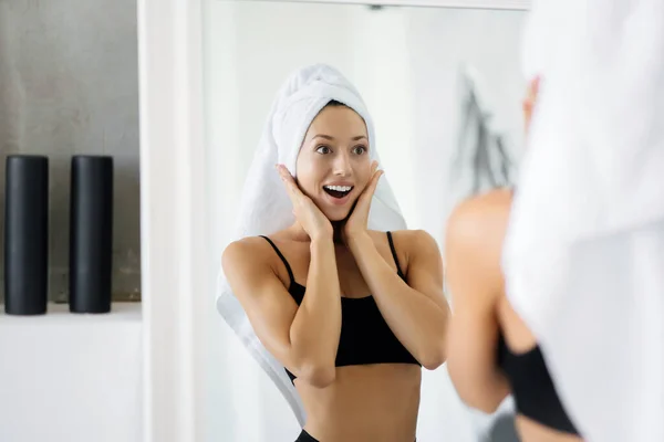 Femme dans la salle de bain avec une serviette sur la tête devant un miroir. — Photo