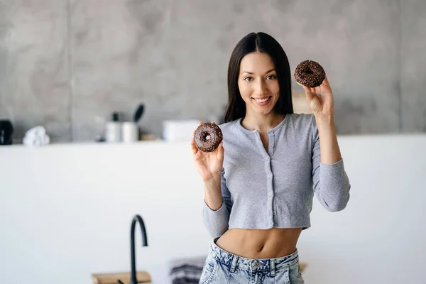 Портрет радісної жінки, що тримає смачний пончик вдома — стокове фото
