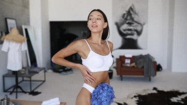 Güzel genç kız iç çamaşırlarıyla oturma odasında poz veriyor.