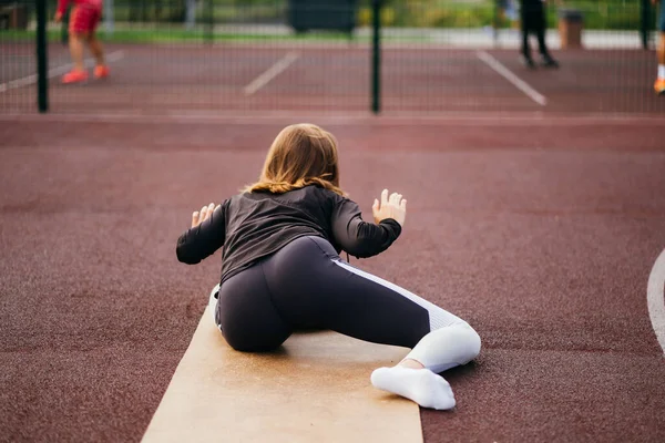 Ung vältränad kvinna i sportkläder tränar utomhus på lekplatsen. — Stockfoto