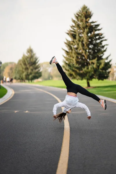 Femme athlète bondissant une fois sur la route, faisant des exercices à l'extérieur. — Photo
