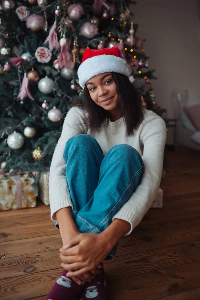 Roztomilý africký americký žena sedí v blízkosti vánočního stromečku — Stock fotografie