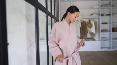 Bir kız banyoda ve bornozunu çıkarıyor.