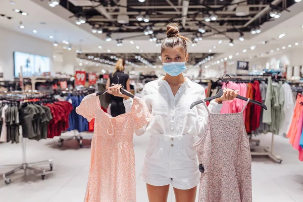 얼굴을 보호하는 마스크를 쓴 옷 부티크를 입고 쇼핑하는 젊은 여자 — 스톡 사진