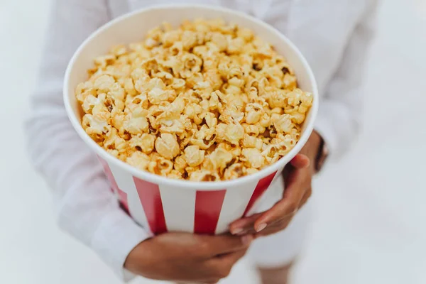 Close-up foto van een jong lief meisje, die een tube popcorn in haar handen houdt. — Stockfoto