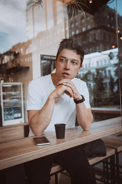 Jonge, knappe man drinkt zijn ochtendkoffie in een café.. — Stockfoto