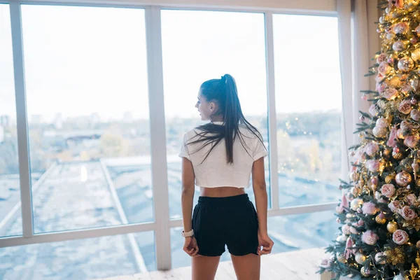 Gadis cantik dalam pakaian olahraga bersandar di jendela. — Stok Foto