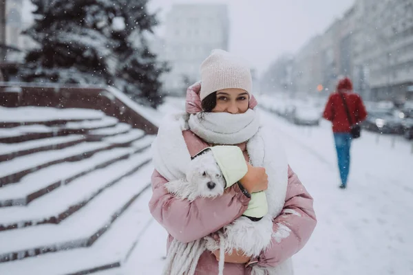 Flicka med en hund i famnen, snön faller — Stockfoto