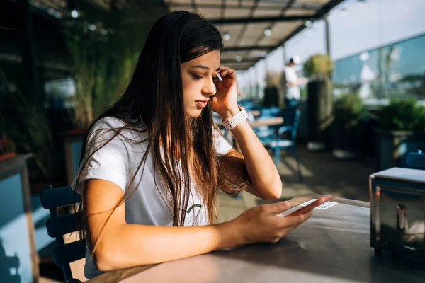 Junge Frau in einem Café mit Smartphone in der Hand — Stockfoto