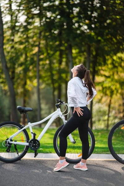 Gyönyörű lány, fehér biciklin pózol. Séta a természetben. — Stock Fotó