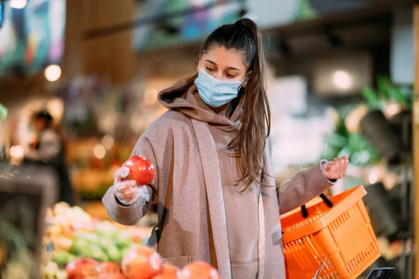 Jovem mulher em máscara protetora faz compras — Fotografia de Stock